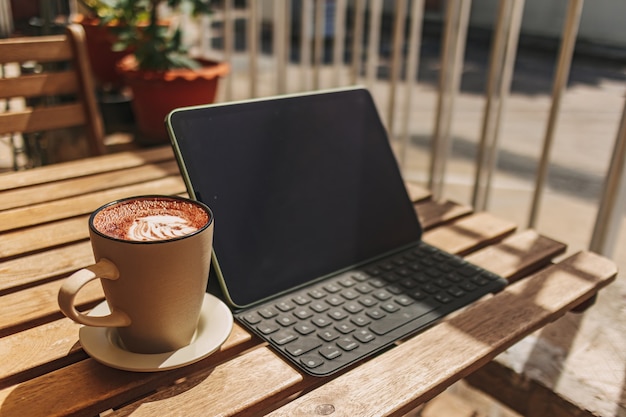 Tablette avec du café chaud sur le bureau avec un chaud soleil d'été