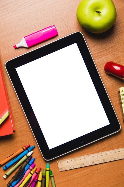Tablette avec écran vide avec fournitures scolaires sur table, vue de dessus