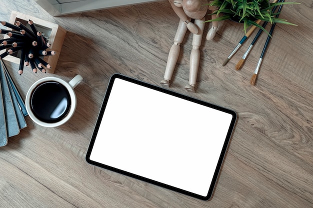 tablette écran vide et fournitures sur table en bois.