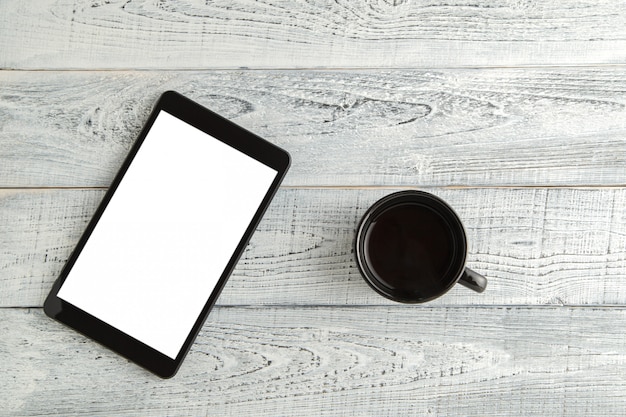 Tablette électronique avec une tasse de thé ou de café sur un vieux bois blanc minable, vue de dessus