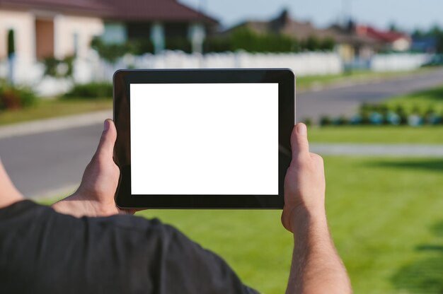 Photo une tablette entre les mains d'un homme, sur fond de maison.