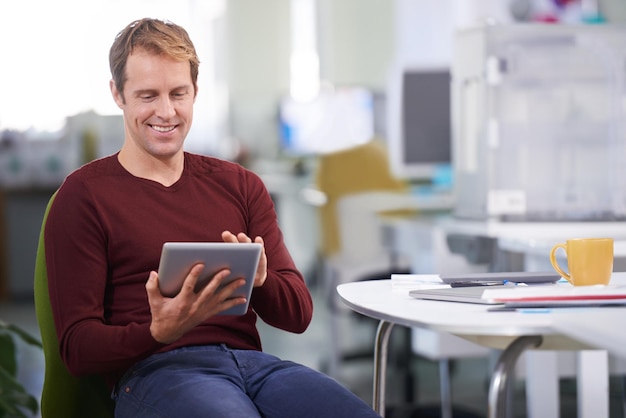 Cette tablette est géniale Un bel homme d'affaires travaillant à son bureau