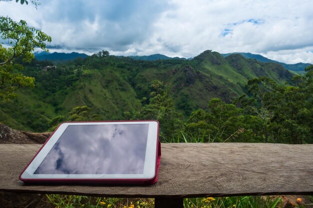 Tablette numérique sur le bureau en bois avec vue sur la montagne