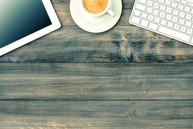 Photo tablette numérique, clavier et tasse de café sur table en bois. maquette. image tonique de style vintage