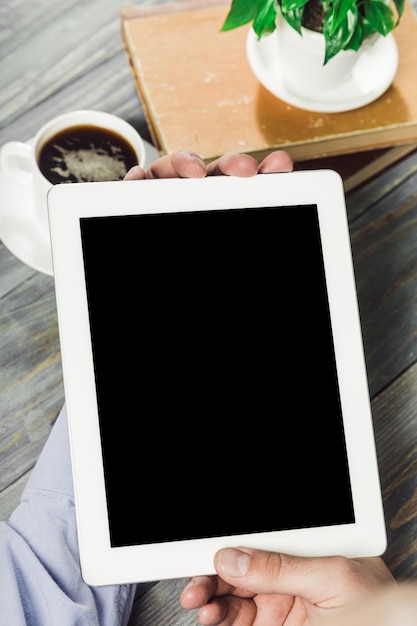 Tablette numérique avec écran isolé dans les mains des hommes sur fond de café - table,