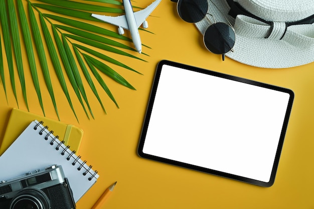 Tablette numérique à plat avec écran vierge et accessoires de voyage sur fond jaune Voyage d'été et concept de vacances
