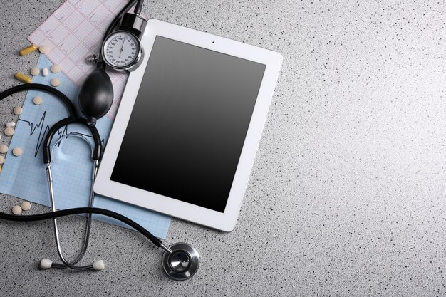 Tablette numérique stéthoscope tensiomètre sur fond gris