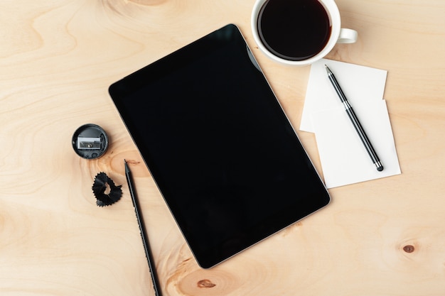 Tablette numérique et tasse de café sur le bureau en bois.