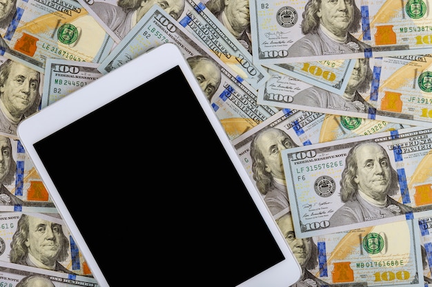 Tablette numérique de technologie et argent comptant sur fond de marbre Concept de dollars américains
