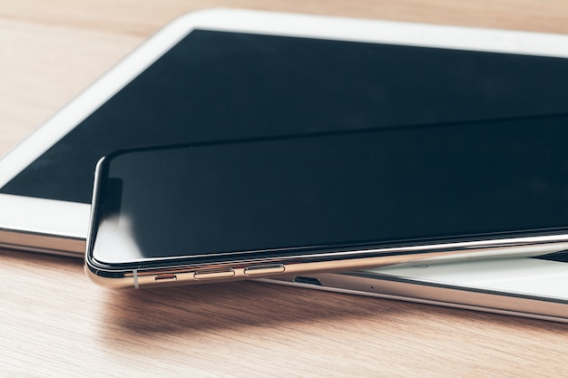 Tablette numérique et téléphone portable. Des appareils électroniques sur une table en bois, se bouchent.