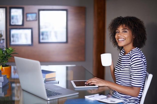 Tablette pour ordinateur portable et portrait d'une femme avec un café pour le travail à domicile, opportunité de carrière de pigiste et travail heureux Visage d'un jeune Africain sur un projet multimédia ou numérique et thé pour l'inspiration