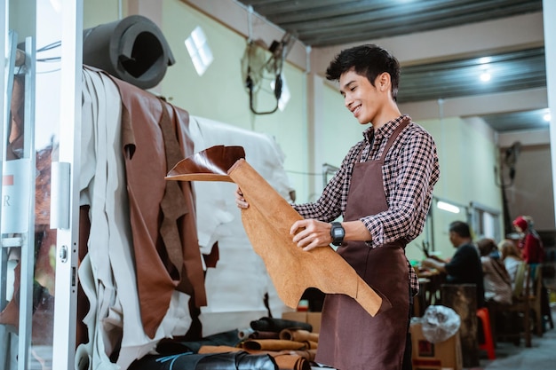 Tablier en artisan vérifiant les feuilles de cuir tanné à l'atelier d'artisanat du cuir