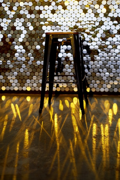 Photo tabouret haut sur une base en métal sur le fond du mur avec des paillettes l'éclat se reflète sur le sol design glamour