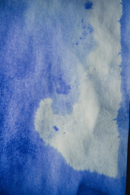Photo tache d'encre bleue sur une feuille de papier blanc macro. abstrait. étale les taches d'encre avec des stries sur un fond blanc. absorber