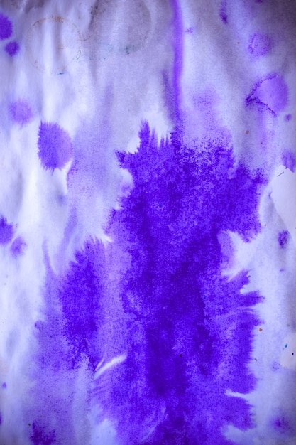 Taches d'encre violette abstraite avec stries sur papier blanc humide