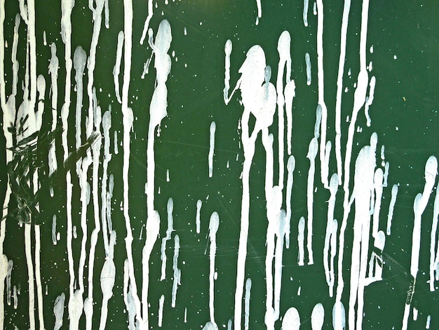 Des taches de peinture blanche sur un mur en plastique vert.