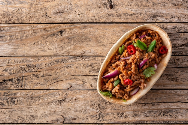 Taco barquita mexicain avec boeuf, piment, tomate, oignon et épices sur table en bois