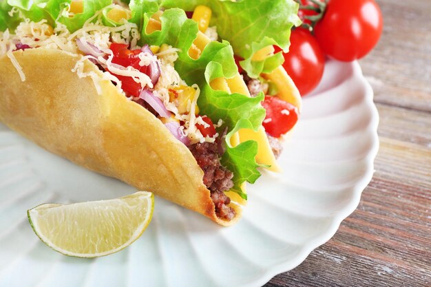 Taco savoureux avec des légumes sur la plaque sur la table en gros plan