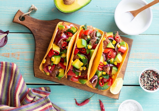 Tacos au porc, avocat, tomates, maïs et oignons. Nourriture mexicaine.