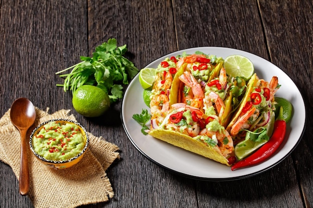 tacos aux crevettes avec salade de chou, citron vert et guacamole sur une assiette