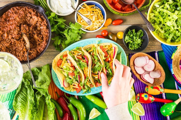 Tacos de boeuf haché avec laitue romaine, tomates en dés, radis et fromage cheddar râpé.