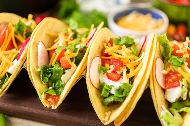 Tacos de boeuf haché avec laitue romaine, tomates en dés, radis et fromage cheddar râpé.