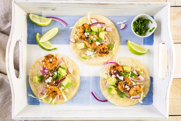 Tacos de crevettes chipotle fraîches avec du fromage cotija sur des tortillas de maïs blanc.