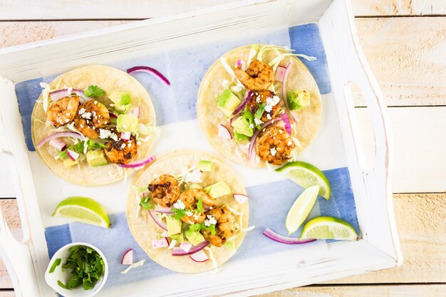 Photo tacos de crevettes chipotle fraîches avec du fromage cotija sur des tortillas de maïs blanc.