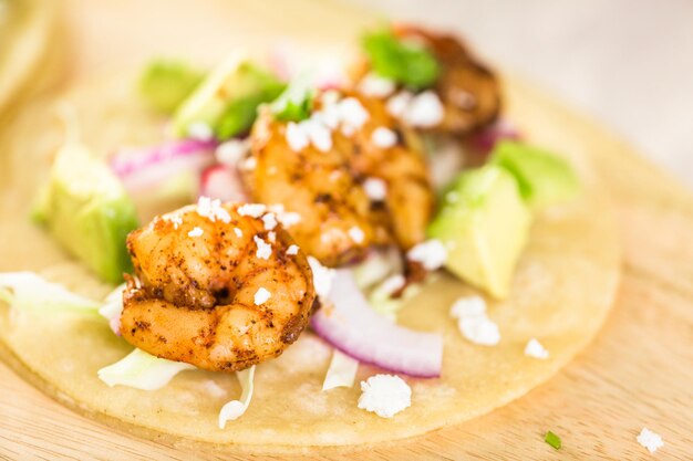 Tacos de crevettes chipotle fraîches avec du fromage cotija sur des tortillas de maïs blanc.