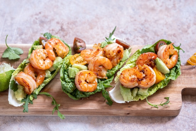 Tacos de crevettes enveloppés de laitue avec tomates fraîches, avocat et citron vert