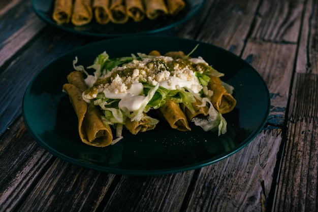 Tacos flauta avec crème au fromage et laitue sur une table en bois Collations mexicaines