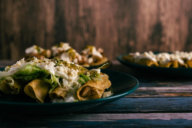 Tacos flauta avec crème au fromage et laitue sur une table en bois Collations mexicaines