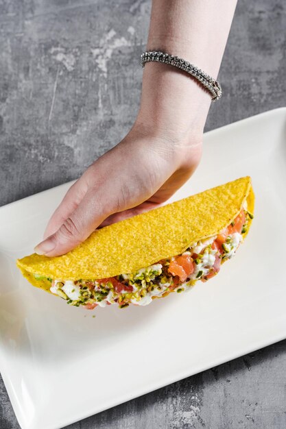 Tacos de maïs avec mayonnaise au saumon et pistaches sur une table en béton et une main féminine