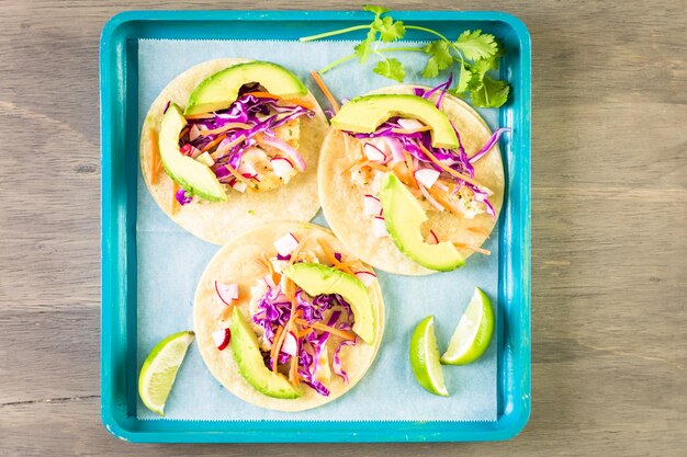 Tacos de poisson frais avec morue et chou violet sur une tortilla de maïs blanc.