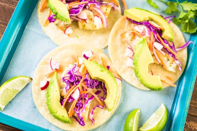 Photo tacos de poisson frais avec morue et chou violet sur une tortilla de maïs blanc.