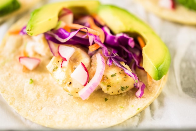 Tacos de poisson frais avec morue et chou violet sur une tortilla de maïs blanc.