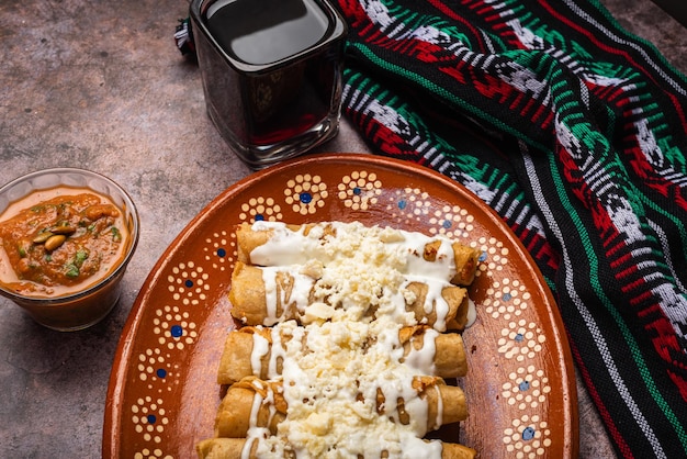Photo tacos de pommes de terre frites avec de la crème et du fromage dans un plat de boue mexicain tacos dorados nourriture mexicaine