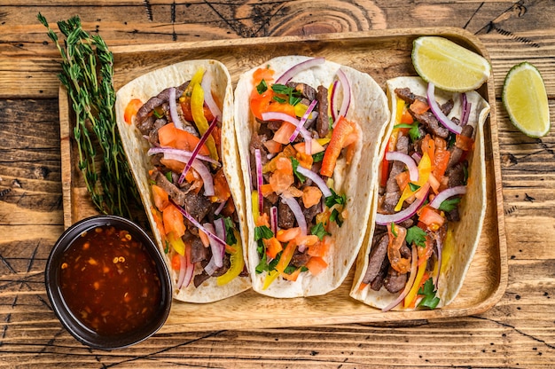 Tacos à la viande de bœuf, oignon, tomate, poivron et salsa. Nourriture mexicaine. fond en bois. Vue de dessus.