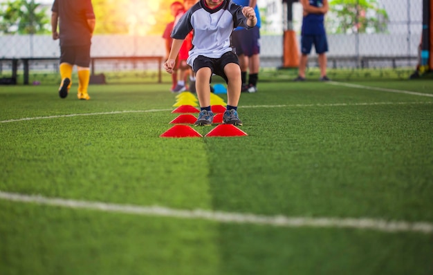 Tactiques de ballon de football sur terrain en herbe avec barrière pour entraîner les enfants à sauter dans l'académie de football