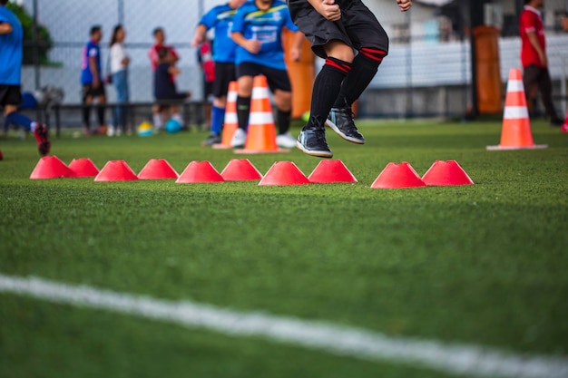 Tactiques de ballon de football sur terrain en herbe avec cône de barrière pour entraîner les enfants à sauter dans l'académie de football