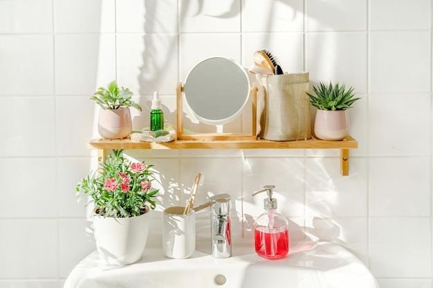 Étagère en bambou avec articles de toilette dans une salle de bains moderne blanche avec un lavabo à côté d'une fenêtre par temps ensoleillé