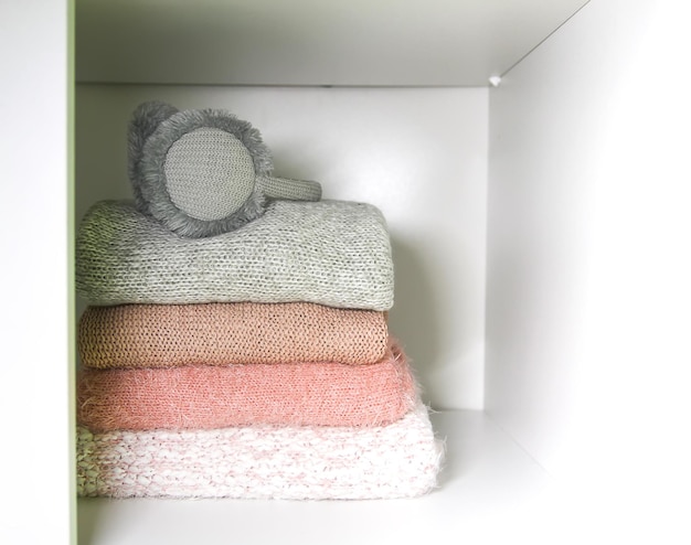 Étagère blanche de la garde-robe de la maison avec des pulls colorés, des pulls et des écouteurs chauds. Petite organisation de l'espace. Notion de minimalisme.