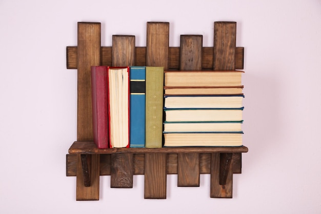 Étagère en bois avec des livres sur fond de mur