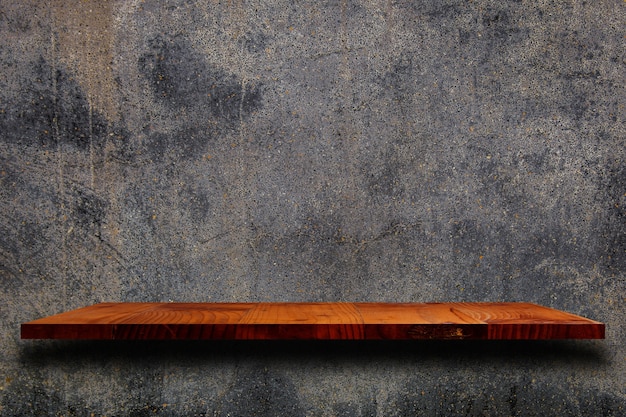 Étagère en bois vide sur le mur de ciment.