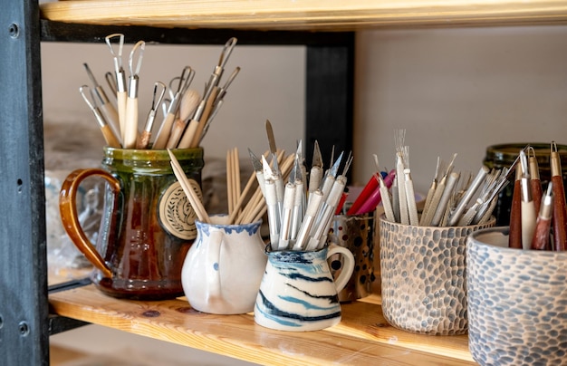 Étagère à poterie en céramique faite à la main avec des plats en céramique et des outils de poterie dans un studio de création