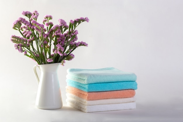 Étagère avec des serviettes propres, des bougies, un pot de fleurs sur fond blanc de la salle de bain