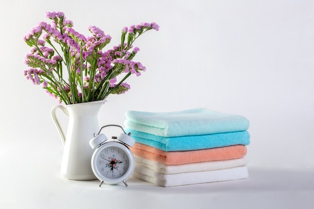 Étagère avec des serviettes propres, des bougies, un pot de fleurs sur fond blanc de la salle de bain