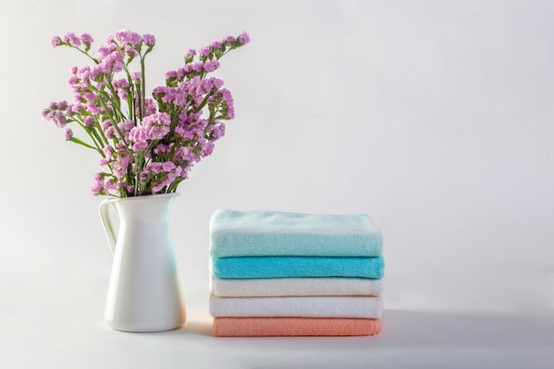 Étagère avec des serviettes propres, des bougies, un pot de fleurs sur fond blanc de la salle de bain