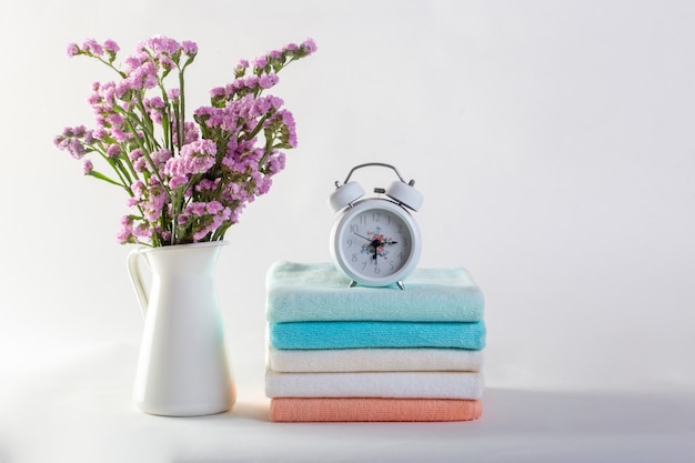 Étagère avec des serviettes propres, des bougies, un pot de fleurs sur fond blanc de la salle de bain