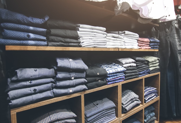 Étagères avec des vêtements en magasin. Sacs, costumes, pantalons, chemises et pulls sur le marché. Journée shopping et vente. Photo de mode.